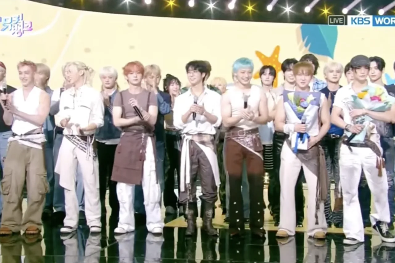Membros do Stray Kids em roupas esportivas, realizando treinos de alta intensidade na academia, com halteres e esteira ao fundo