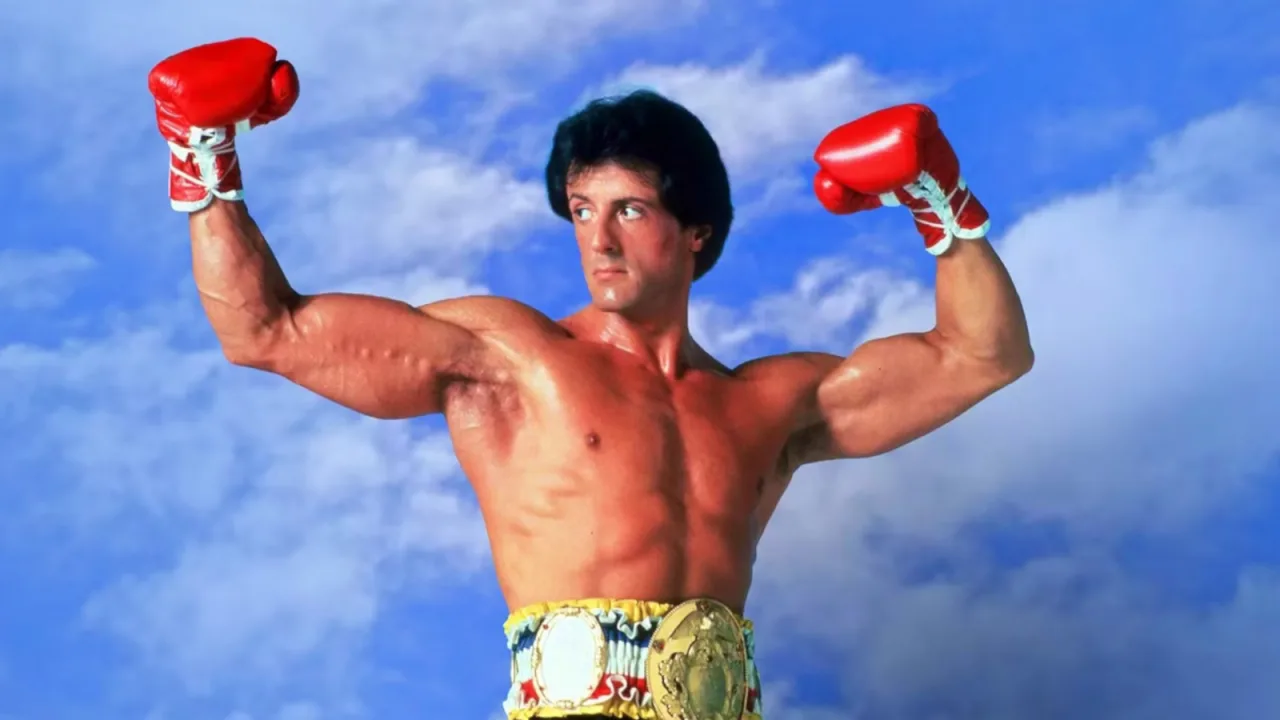 Botas Nike de boxe customizadas de Rocky III apoiadas sobre um saco de pancadas, com luvas e corda de pular ao fundo