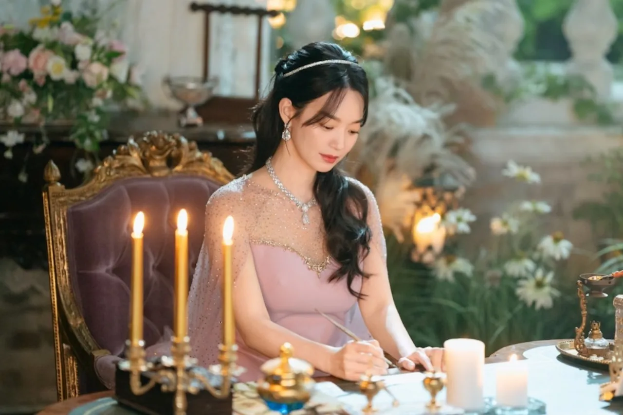 Shin Min Ah como Navier usa trajes luxuosos, penteado elaborado e expressão que combina autoridade e vulnerabilidade