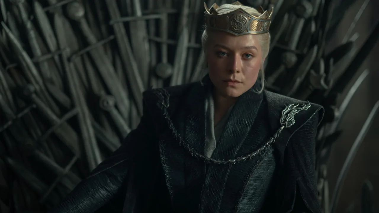 Rhaenyra empunhando espada ao ar livre, vestida de armadura leve, ao lado de halteres de ferro