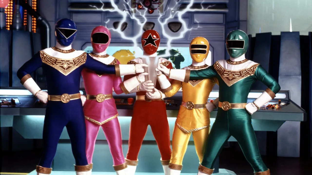 Homem em roupa de academia levanta halteres ao lado da figura Gold Zeo Chrome sobre o chão