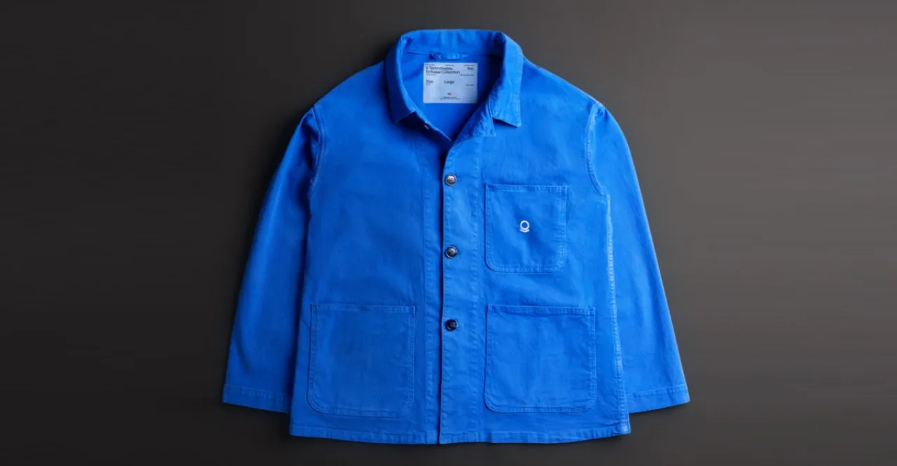 Modelo veste a jaqueta chore coat da Palantir segurando um suco verde e um tapete de ioga em um ambiente arborizado