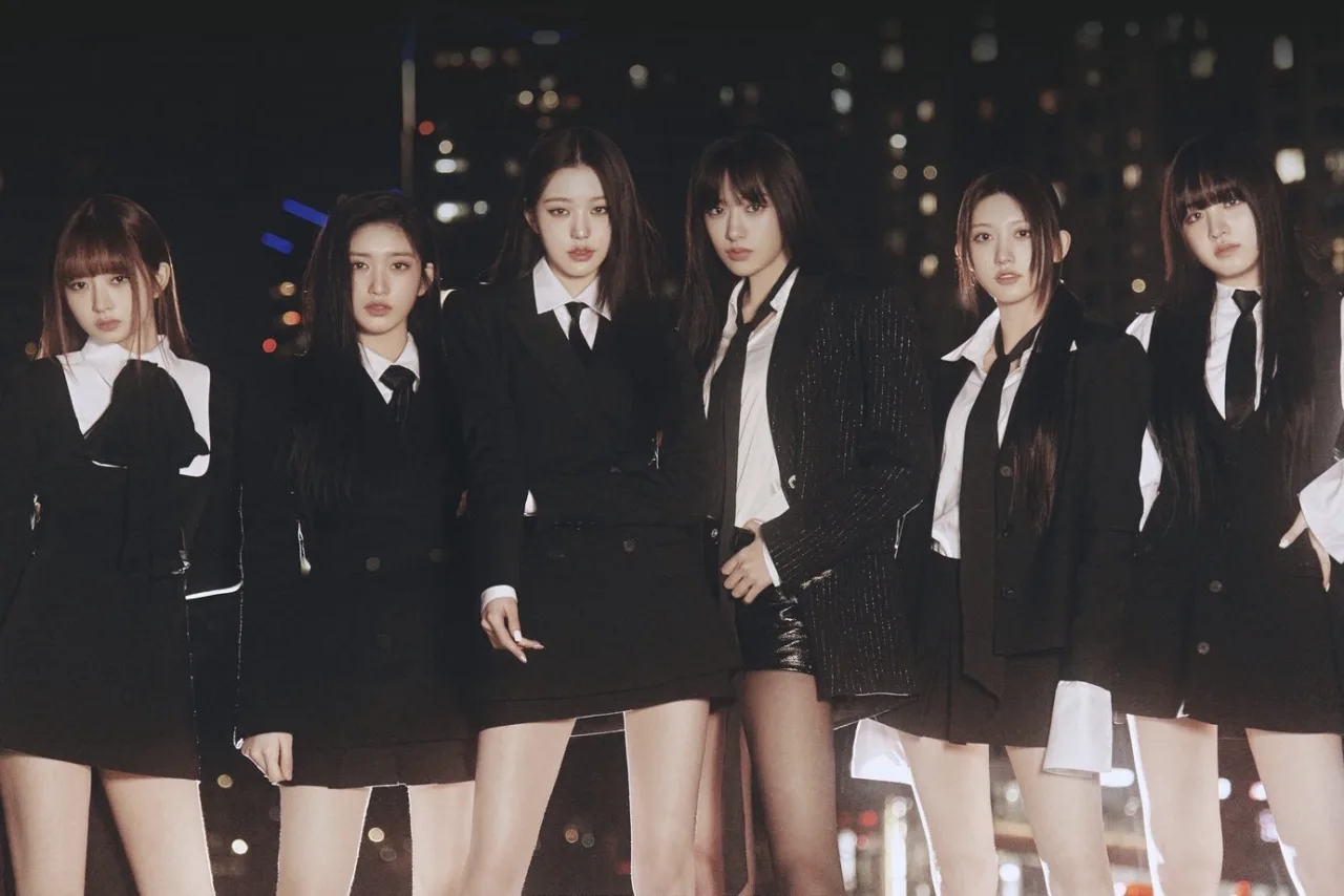 Jovem mulher faz agachamento com fones, tela mostrando o clipe 'I AM' da IVE ao fundo