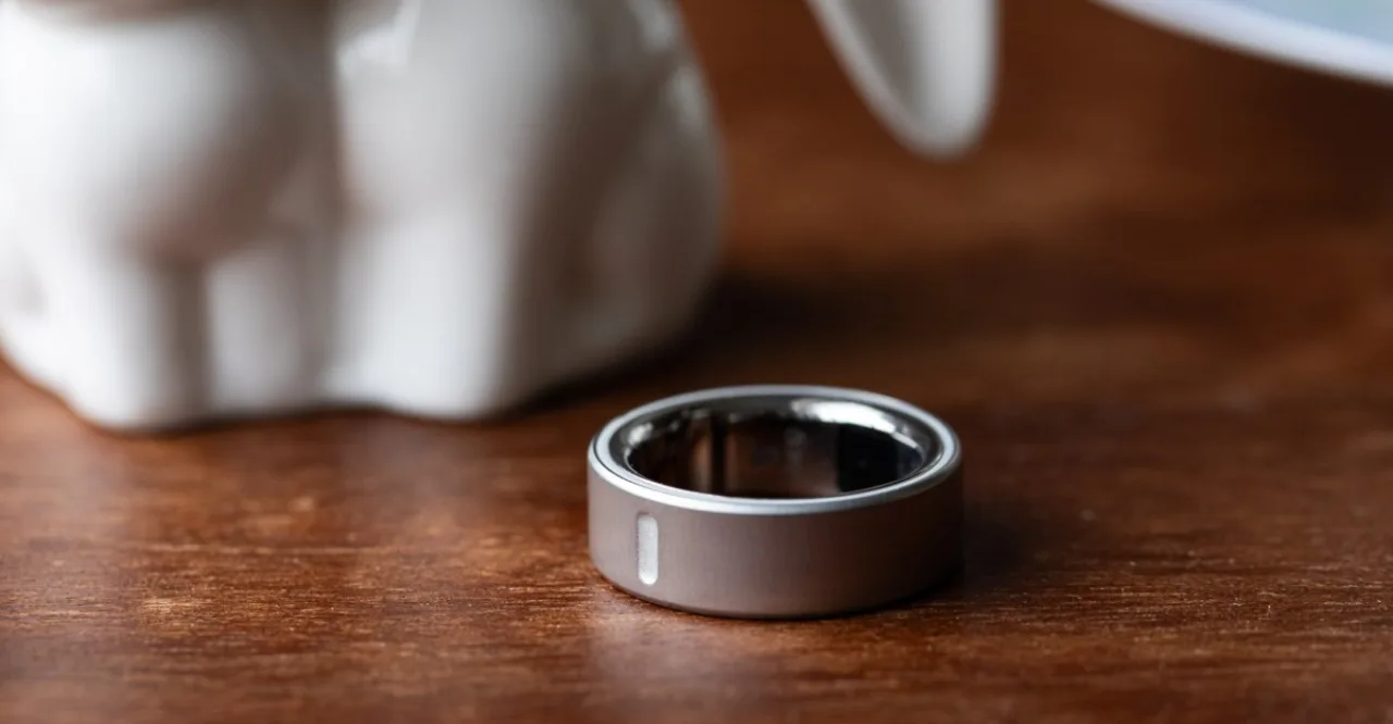 Mulher correndo na esteira usando Oura Ring 4, com caixa do aparelho e garrafa d'água ao fundo