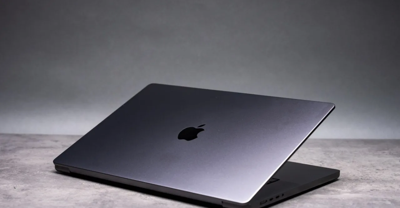 MacBook Pro de alumínio com tela sensível ao toque exibindo o logotipo da Apple sobre fundo escuro