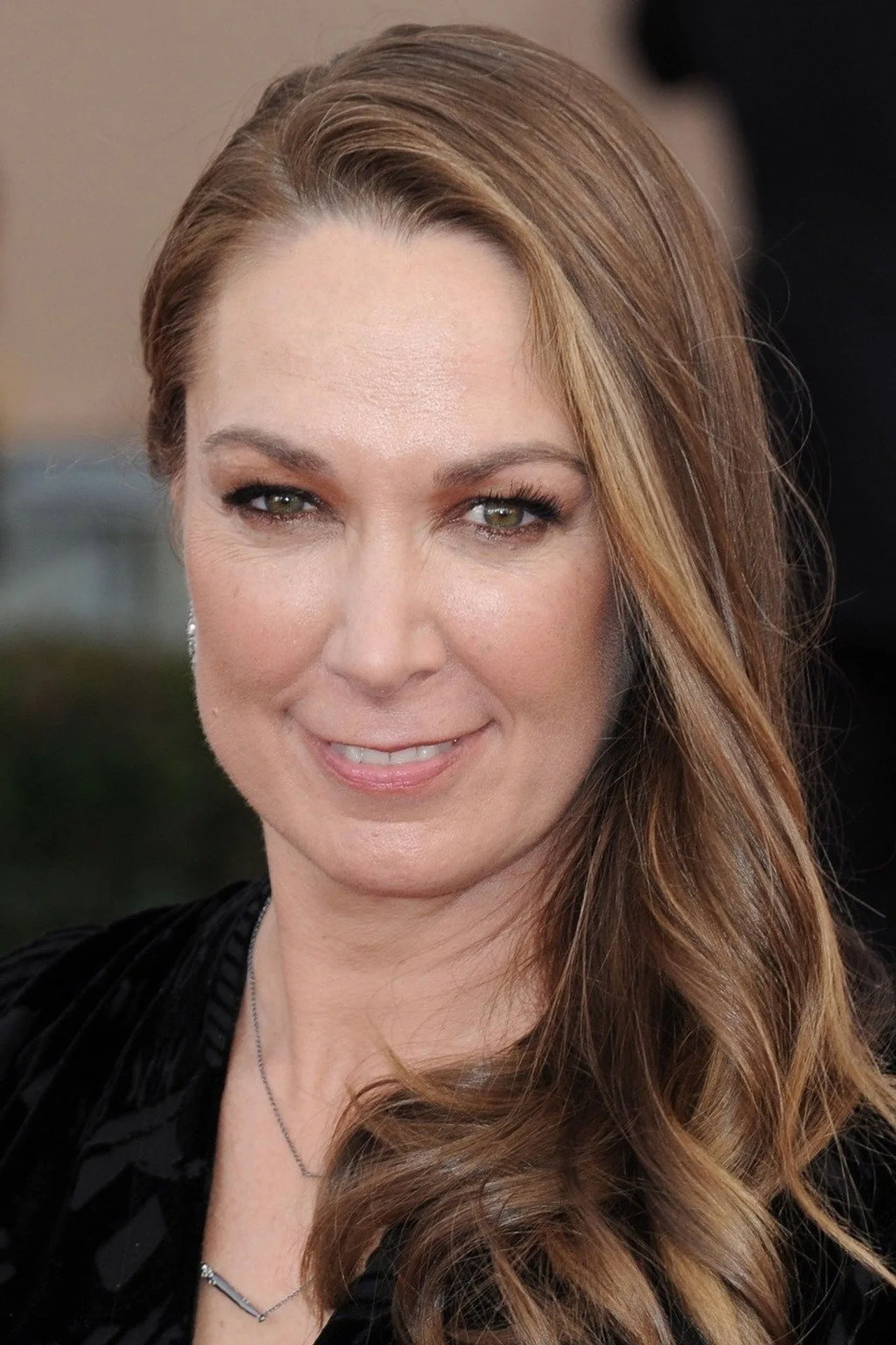 Elizabeth Marvel vestindo roupa de treino, segurando halteres, em estúdio iluminado