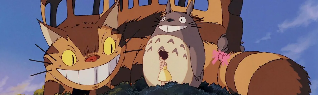 Jovem em roupa de Totoro faz alongamento com halteres ao lado de TV exibindo anime