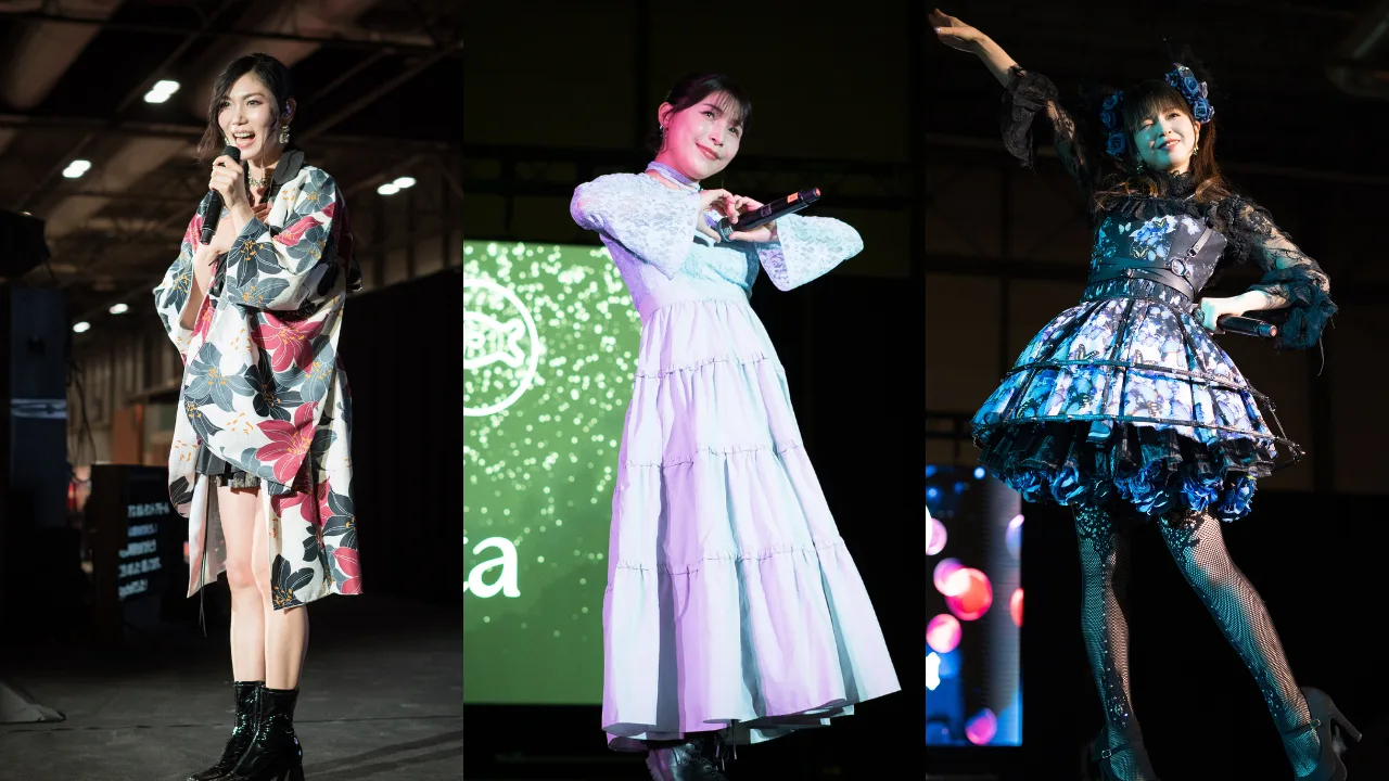 Raychell, Emi Nitta e Haruna Luna cantando energicamente, vestidas com roupas vibrantes, segurando microfones sob luzes de palco