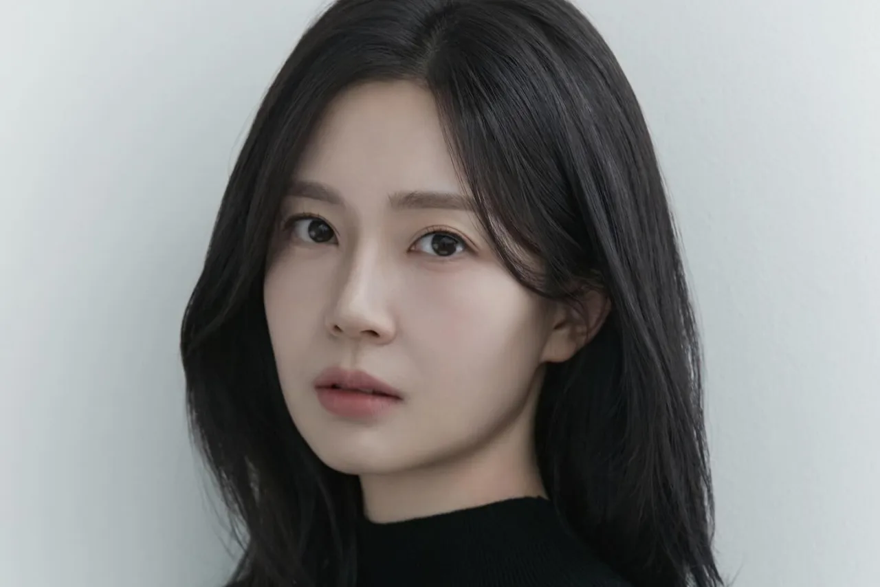 Baek Jin Hee segura uma carta manuscrita, sorrindo, com um anel de casamento ao lado, em fundo suave