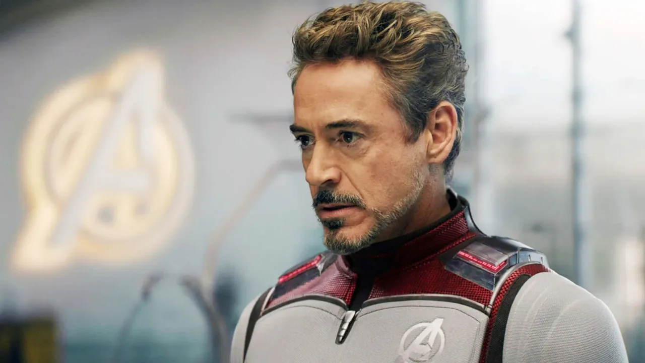 Um fã em camiseta dos Vingadores levanta um haltere com o símbolo da Manopla do Infinito ao fundo da nova atração