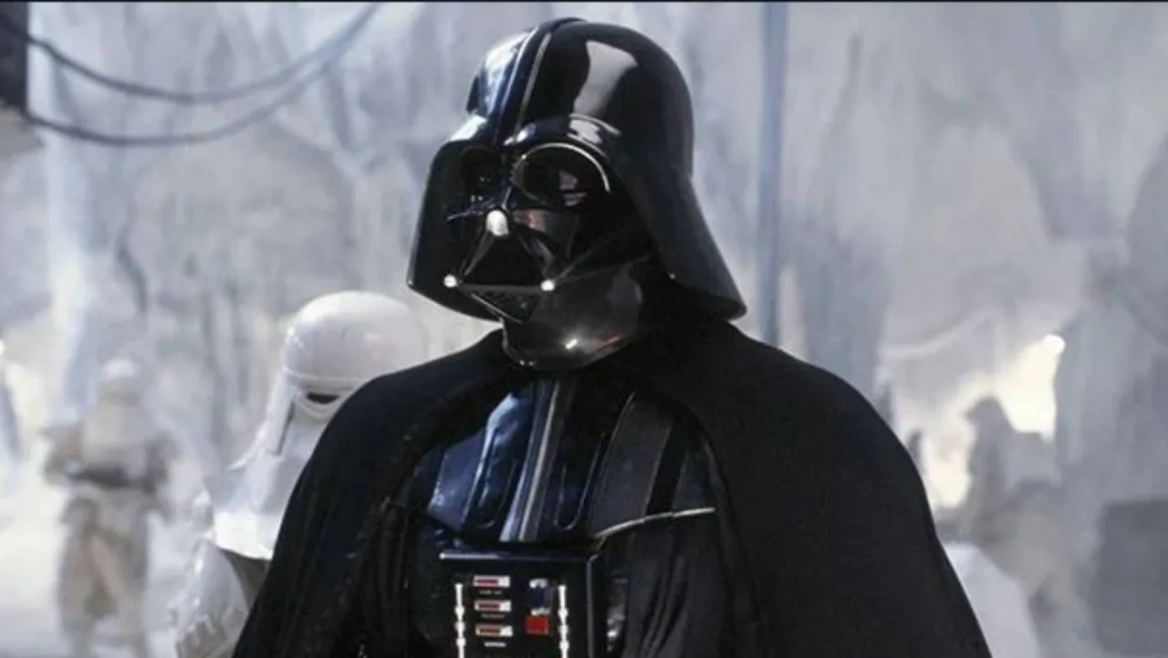 Homem em roupa de treino segurando miniaturas de Darth Vader, Yoda e IG‑88 como pesos na academia