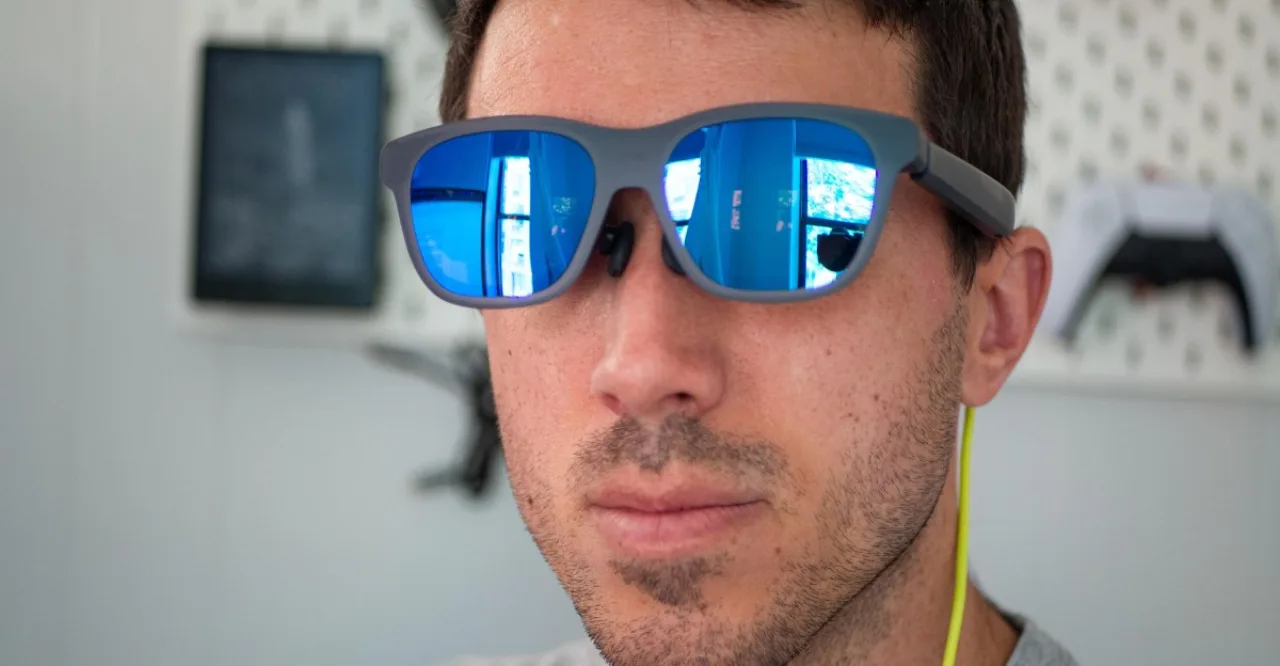 Um usuário testa os óculos Xreal enquanto vê cenas coloridas em 3D projetadas numa TV de tela plana