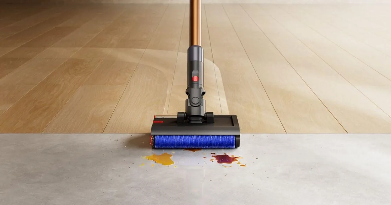 Mulher em roupa esportiva limpando o piso de madeira com o Dyson PencilWash, segurando uma garrafa de água