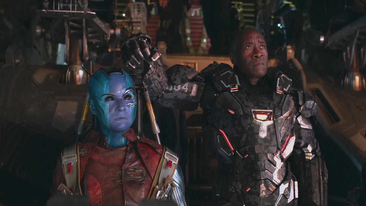 Homem musculoso vestindo camiseta do Capitão América levanta halteres ao lado de pôster de Endgame Encore