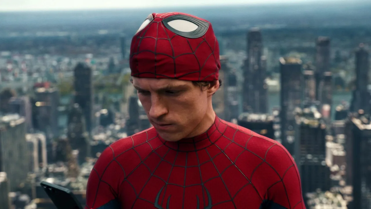 Pessoa vestindo camiseta de treino com logo de aranha, fazendo flexão de braços ao lado de um notebook aberto