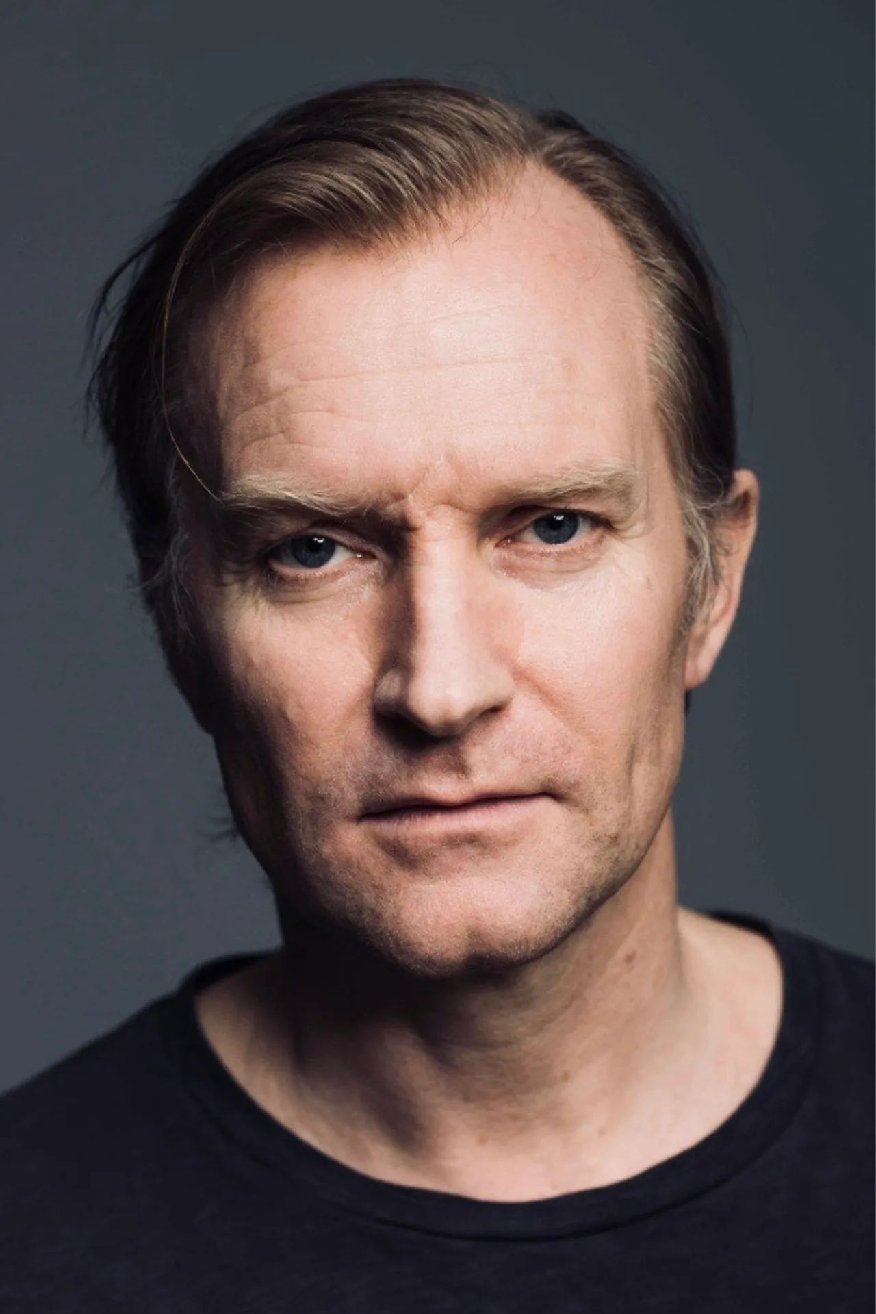 Ulrich Thomsen vestindo capa amarela de Sinestro faz agachamento com halteres ao lado de um anel de energia verde