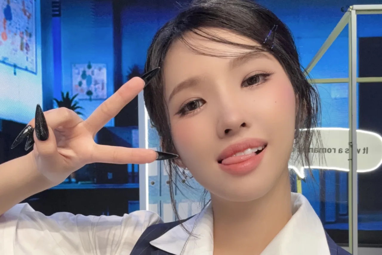 Soyeon, da (i‑dle), segura o troféu de 1º lugar no palco iluminado do M Countdown, ao lado do logo do programa