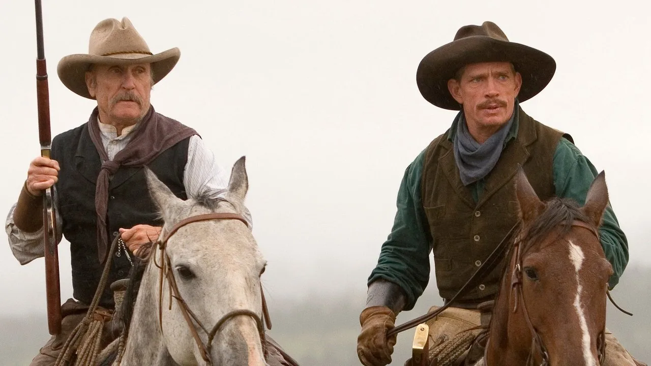 Homem em traje de cowboy faz agachamento com kettlebell ao fundo, TV exibindo cena de Broken Trail