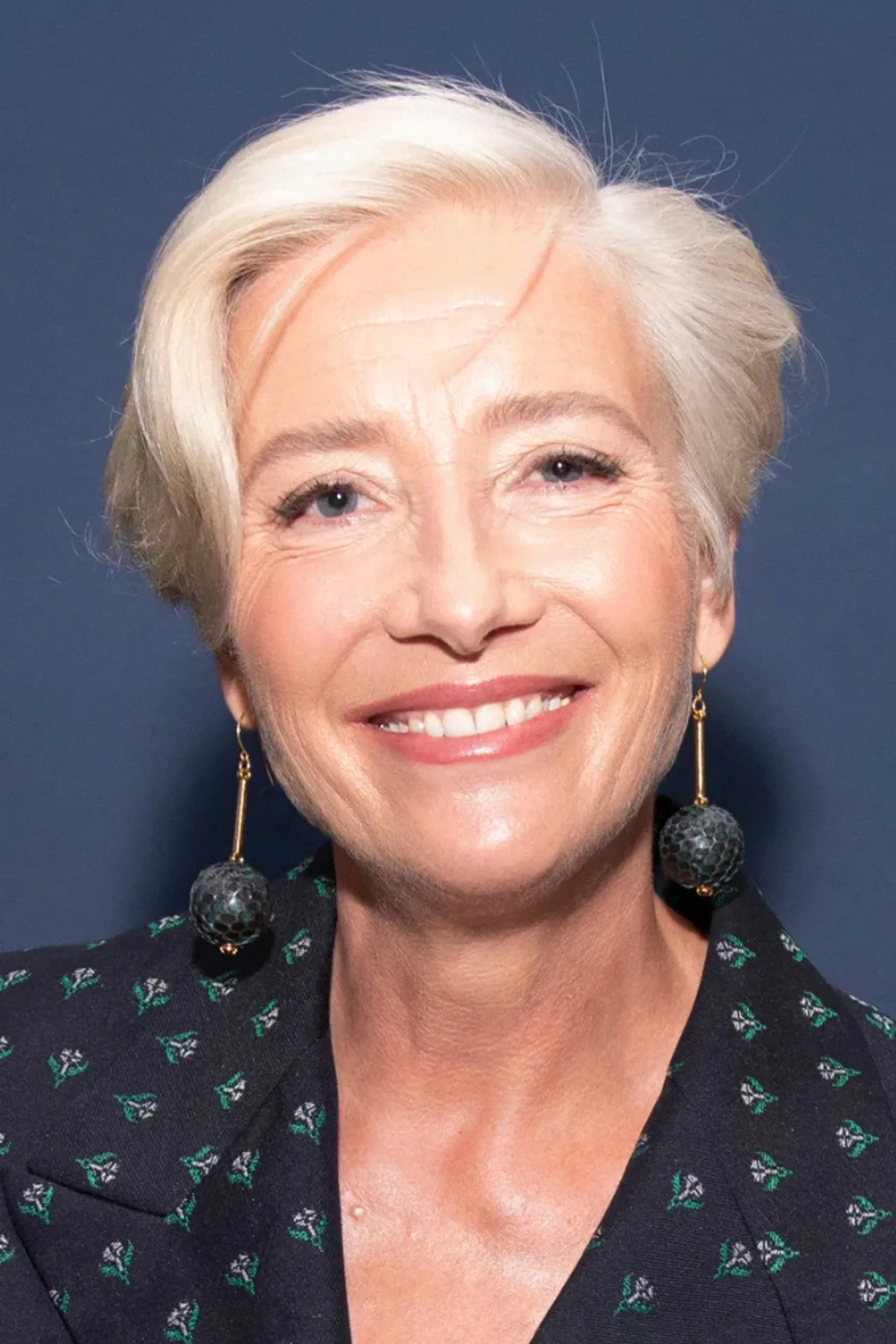 Emma Thompson vestida com jaqueta térmica, segurando halteres enquanto corre em neve ao fundo de uma floresta gelada