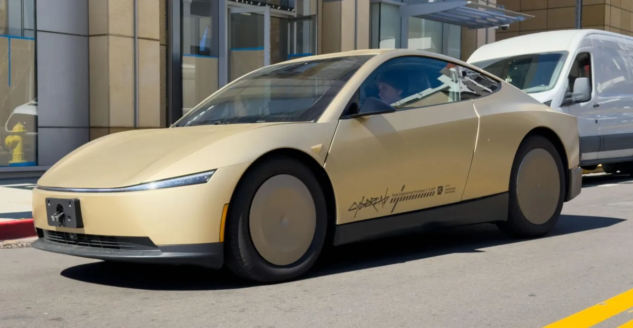 Um Tesla robotaxi vermelho passa perto de um sinal de zona escolar com faixa de pedestres e crianças ao fundo
