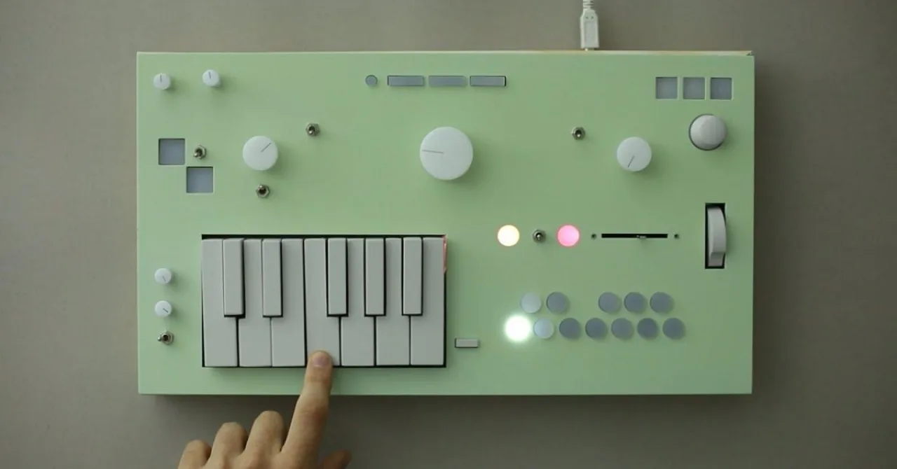 Synth Nopia Synth em destaque sobre mesa de estúdio, cercado por teclados, fones de ouvido e cabos coloridos