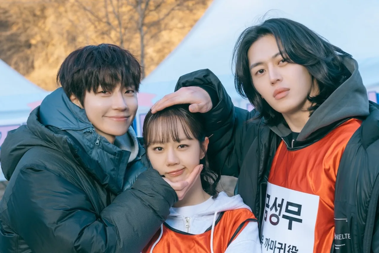 Hwang In‑Youp e Hyeri sorrindo enquanto fazem alongamento de braço com garrafas de água ao lado