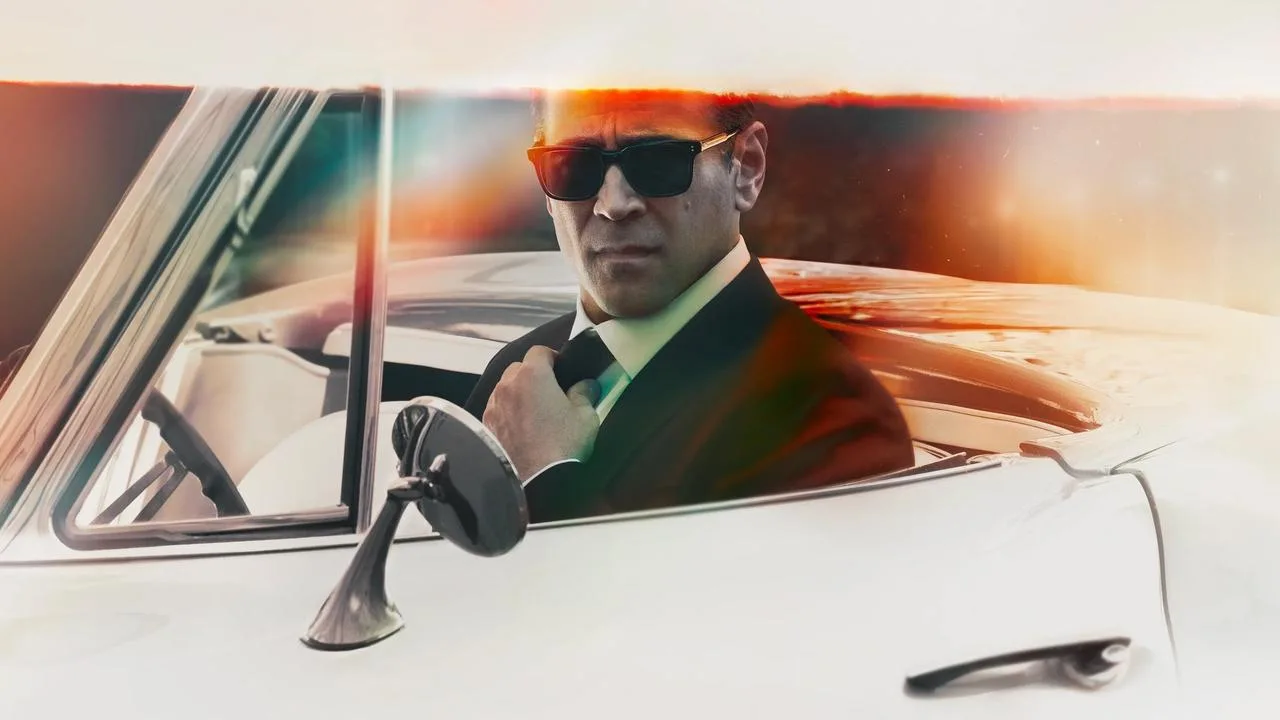 Colin Farrell segurando uma garrafa de água ao lado de halteres em um estúdio iluminado