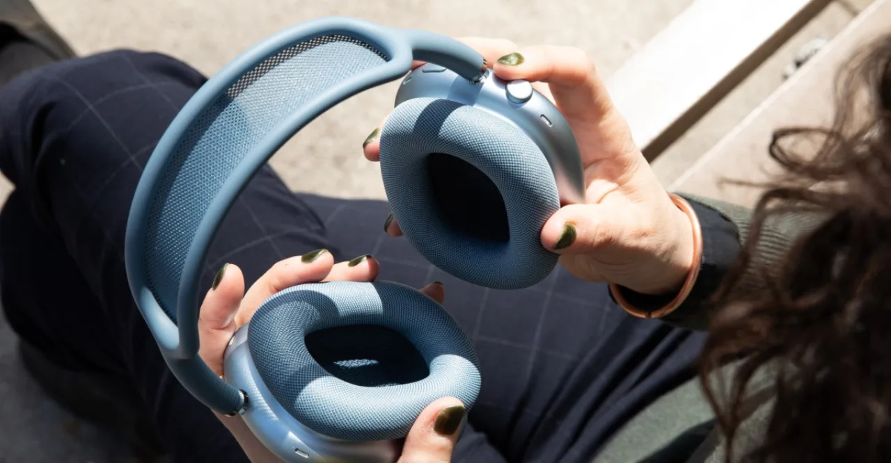 Jovem correndo na pista ao pôr‑sol usando AirPods Max 2, garrafa d'água e pulseira fitness visíveis
