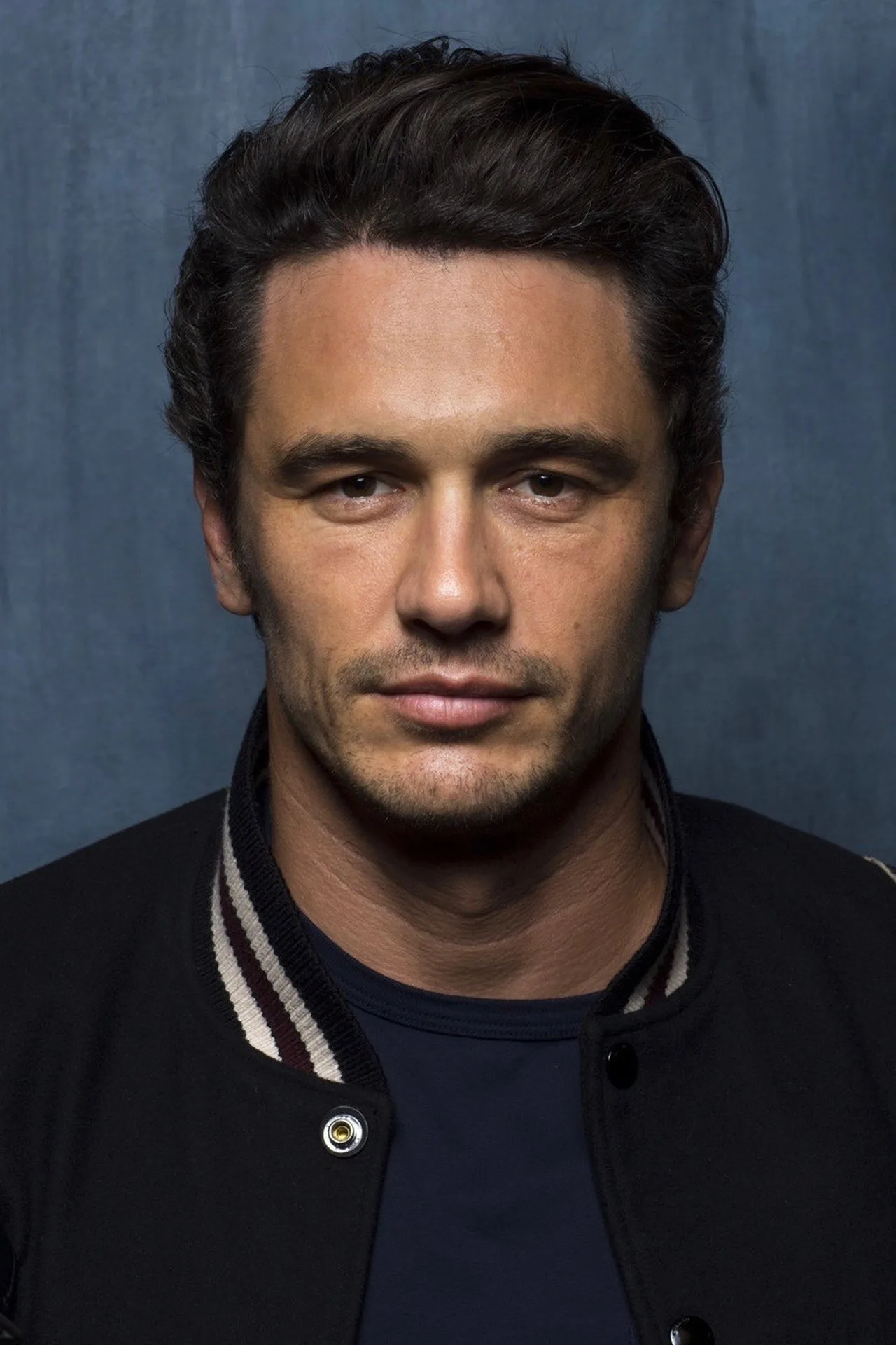 James Franco treinando intensamente com halteres em uma academia rústica, cercado por pesos e equipamentos de metal