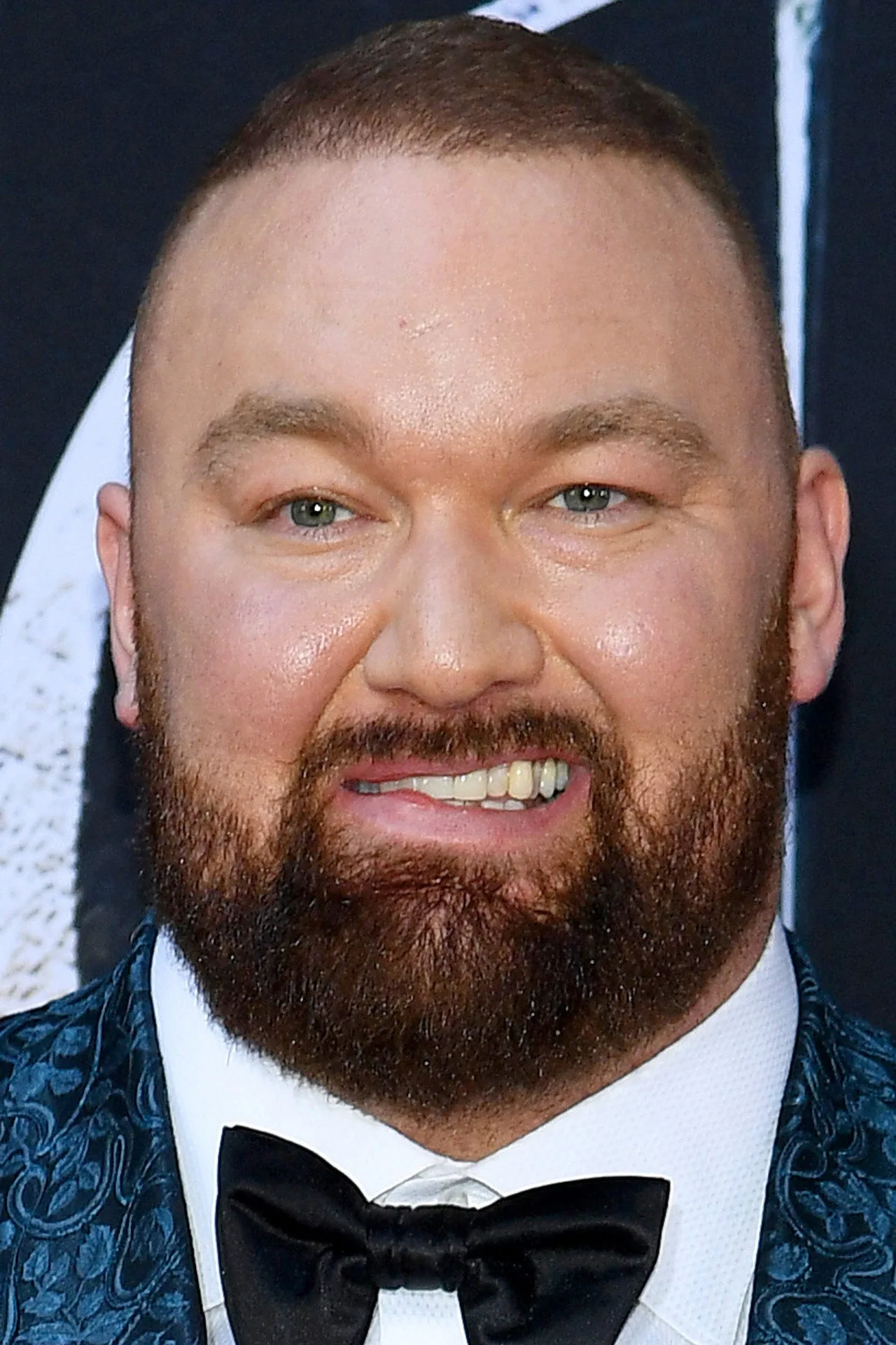 Hafþór Björnsson sentado em cadeira de maquiagem, rodeado por próteses detalhadas e pincéis de caracterização