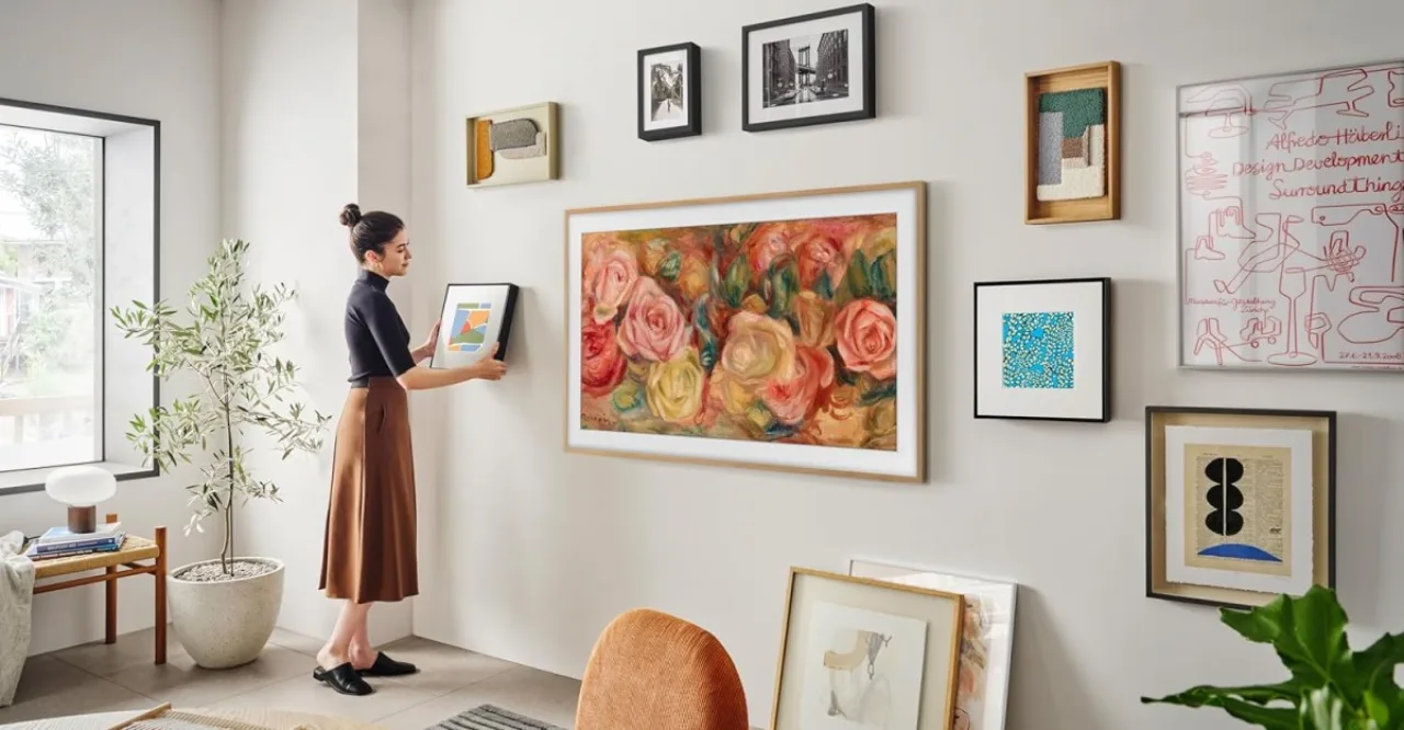 Sala moderna com sofá cinza, a TV Samsung Frame 55'' exibindo pintura abstrata e um tapete bege