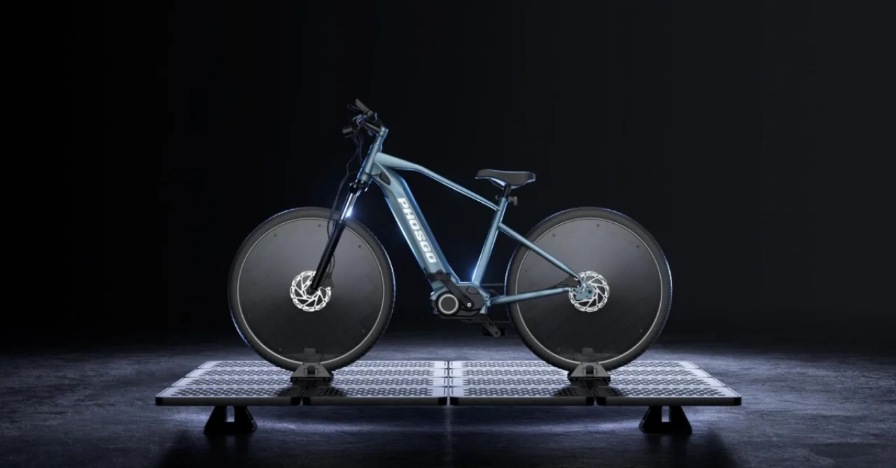 Ciclista sorrindo, vestindo roupa esportiva, pedalando uma e‑bike branca com painel solar sob luz do sol