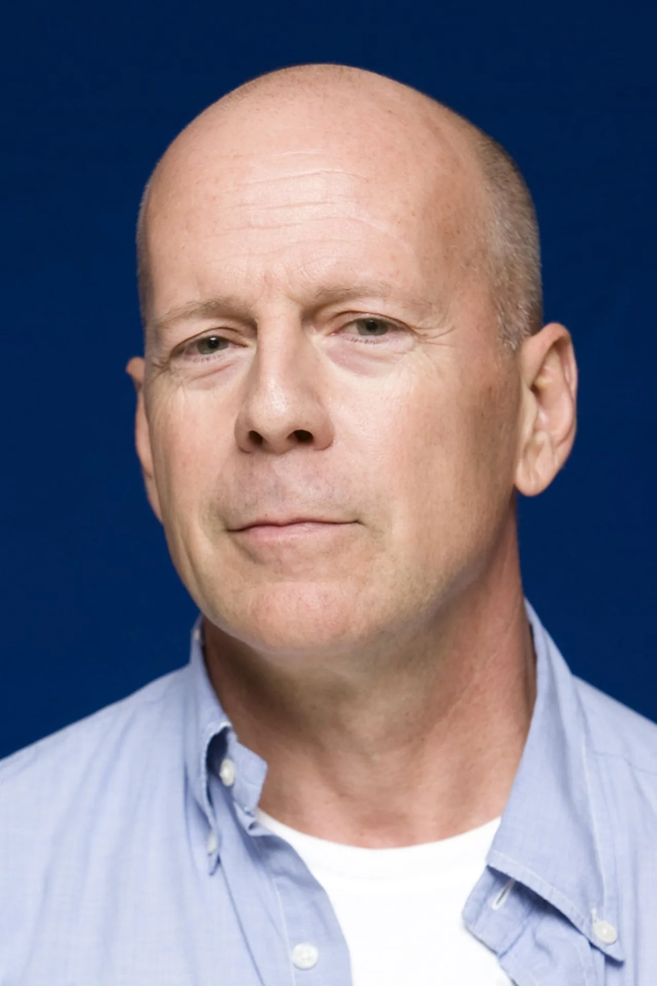 Bruce Willis em postura de combate, braços fortes e suados sob farda militar, segurando fuzil em névoa esverdeada