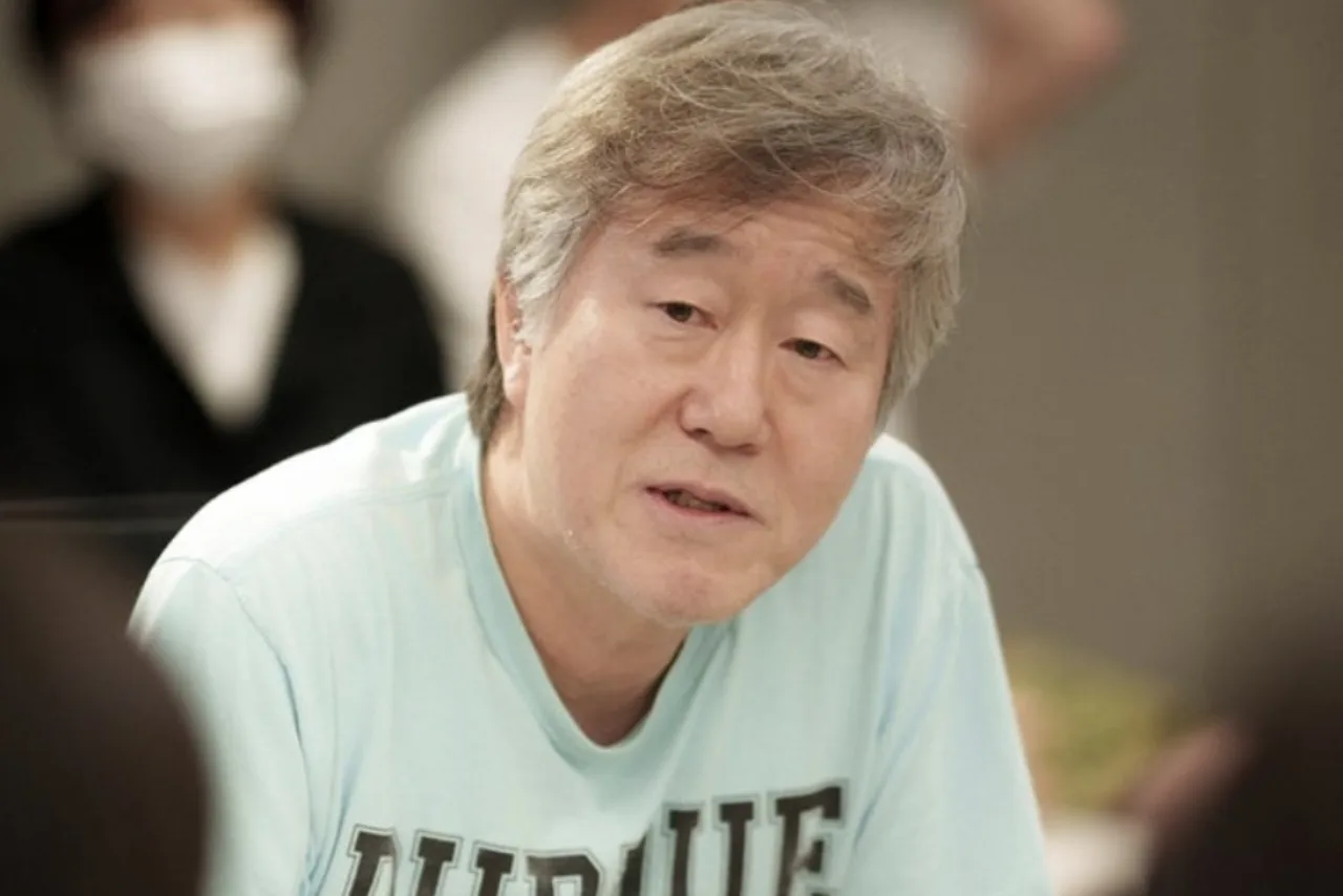 Homem de 60 anos correndo na esteira, suado, segurando garrafa de água e usando camiseta de performance
