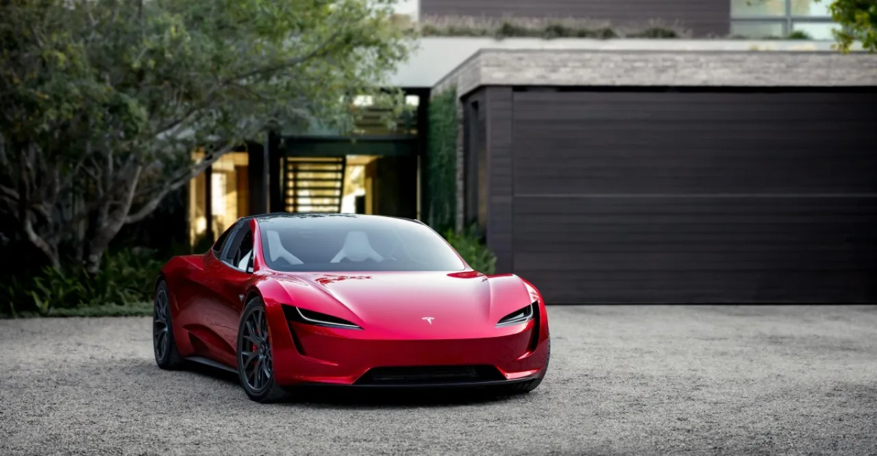 Tesla Roadster vermelho sobre a linha de montagem da fábrica de Waco, com o logotipo da Tesla ao fundo