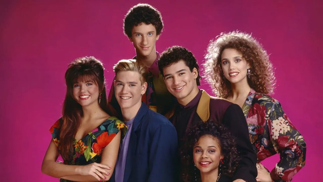 Jovem em leggings faz agachamento com halteres ao fundo, enquanto a TV exibe a abertura de Saved by the Bell