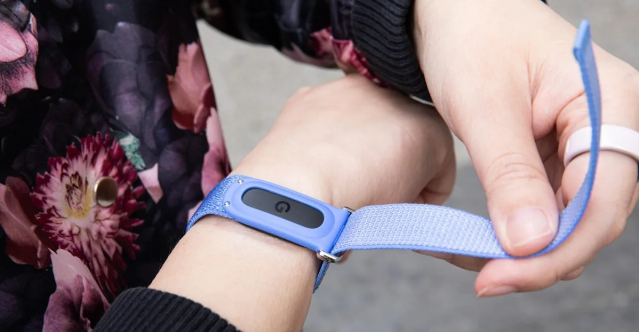 Um smartwatch Fitbit conectado ao iPhone, exibindo tela de passos e frequência cardíaca ao lado do app Apple Health aberto