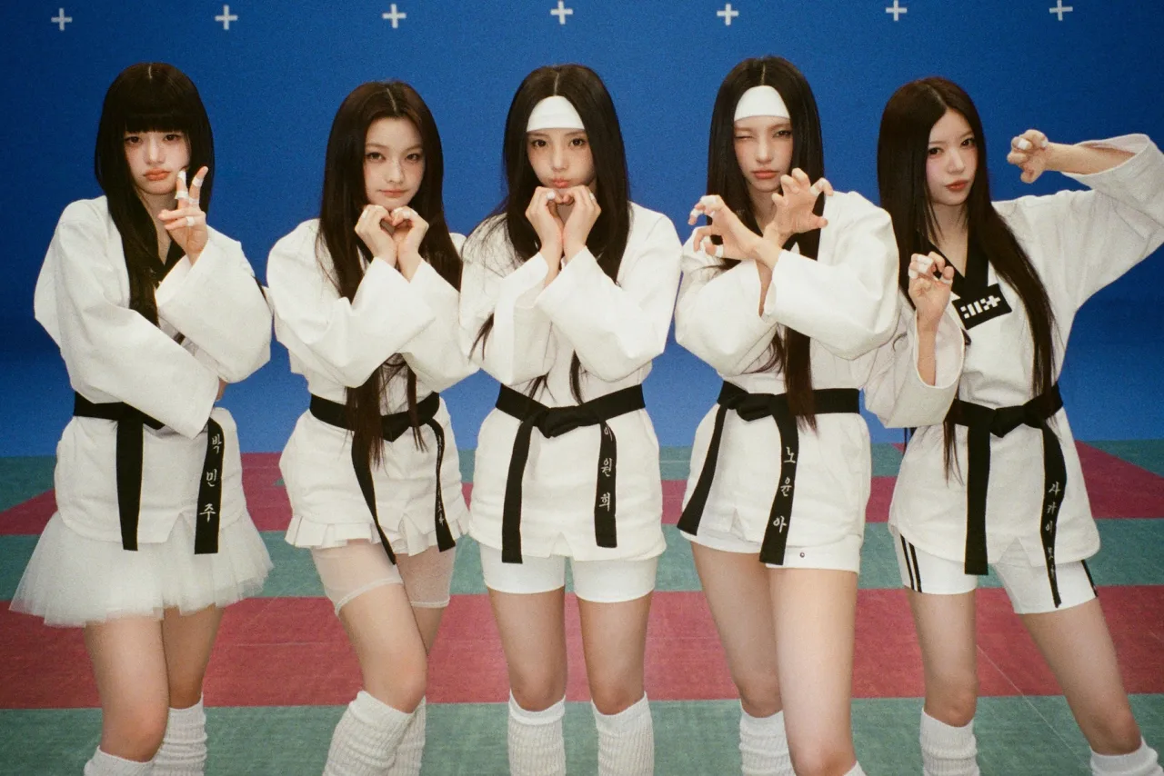 Membros da ILLIT posam em cenário neon do clipe 'It's Me', com logo da banda e contagem de 200 milhões de visualizações