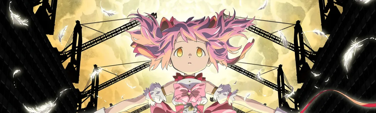 Jovem fazendo agachamento com barra, ao lado de dois plushes gigantes de Madoka e Homura sobre o tapete