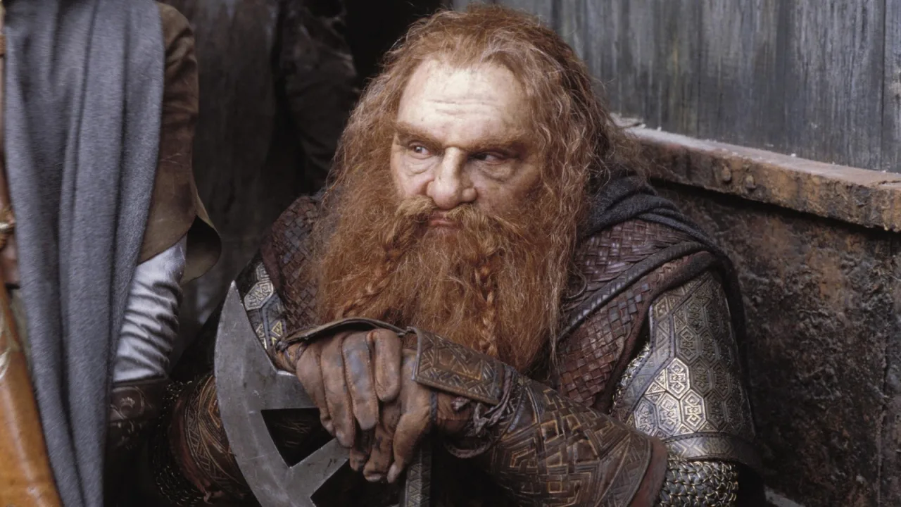 Homem de meia-idade vestindo camiseta de Tolkien, segurando o livro enquanto faz flexão de braço