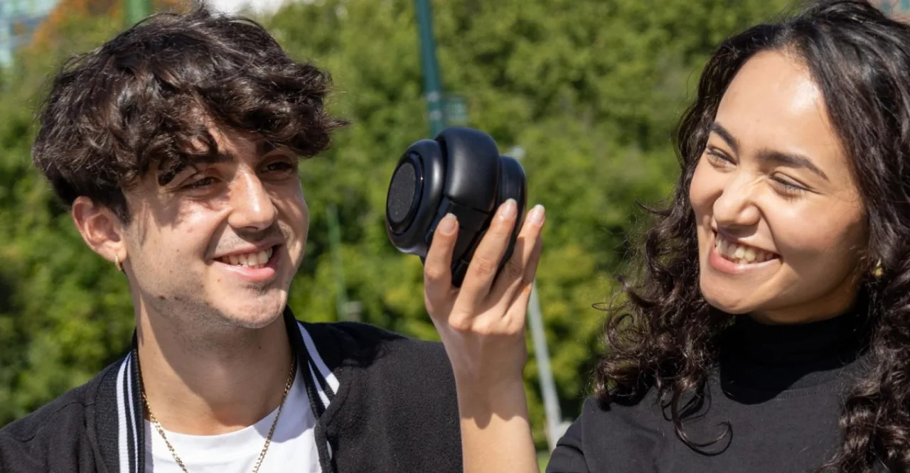 Fones TDM Neo enrolados ao lado do logo da Tomorrow Doesn’t Matter, exibidos em um stand iluminado do CES 2026