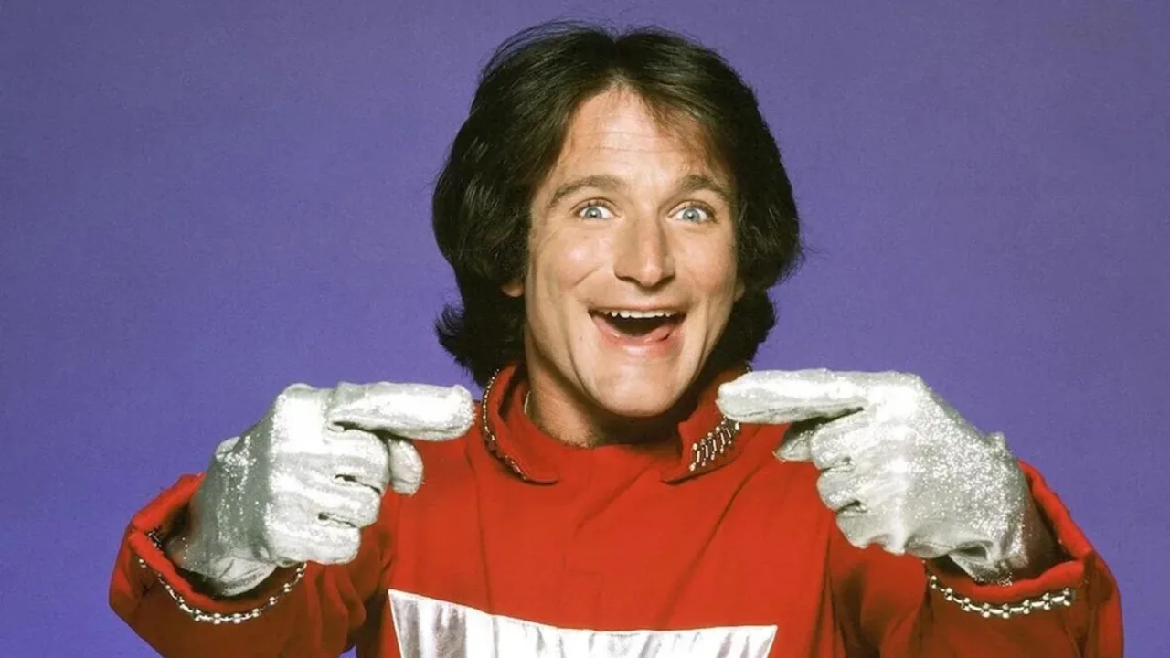 Robin Williams como Mork, em seu traje azul, ao lado dos logotipos de Happy Days, Mork & Mindy, The Cosby Show e Family Ties