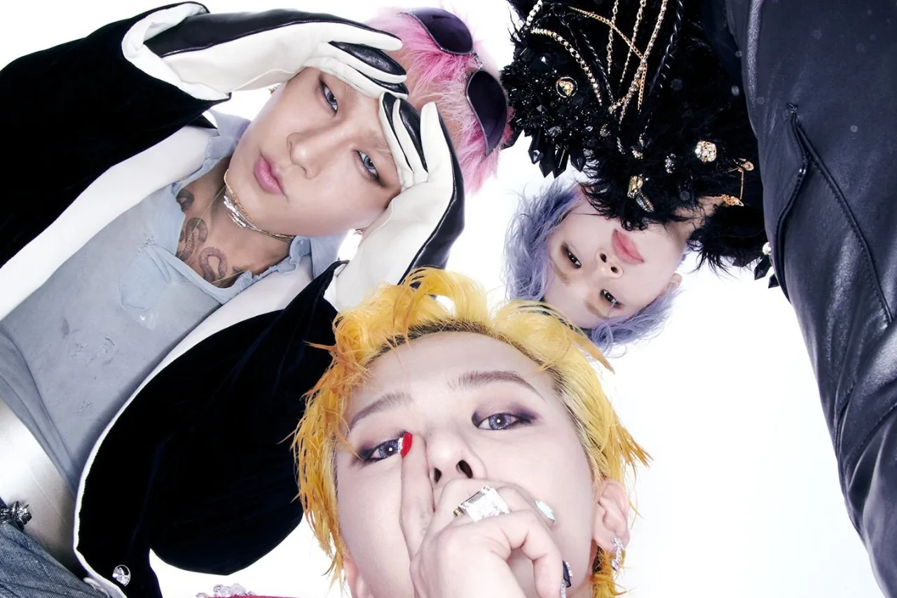 Membros do BIGBANG segurando halteres enquanto exibem o troféu BiiiG no palco