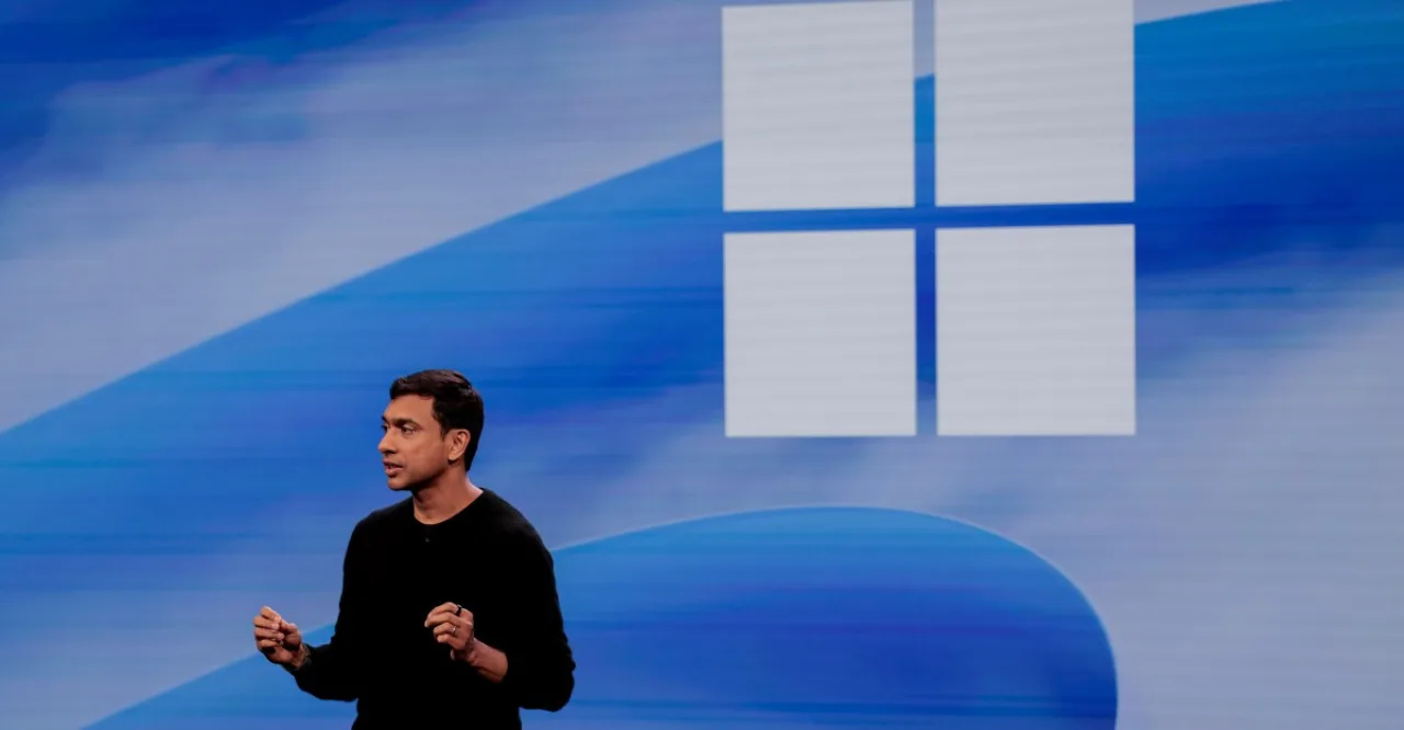 Tela de PC exibindo a barra de tarefas do Windows 11 ao lado de um holograma de IA e o logotipo da Microsoft