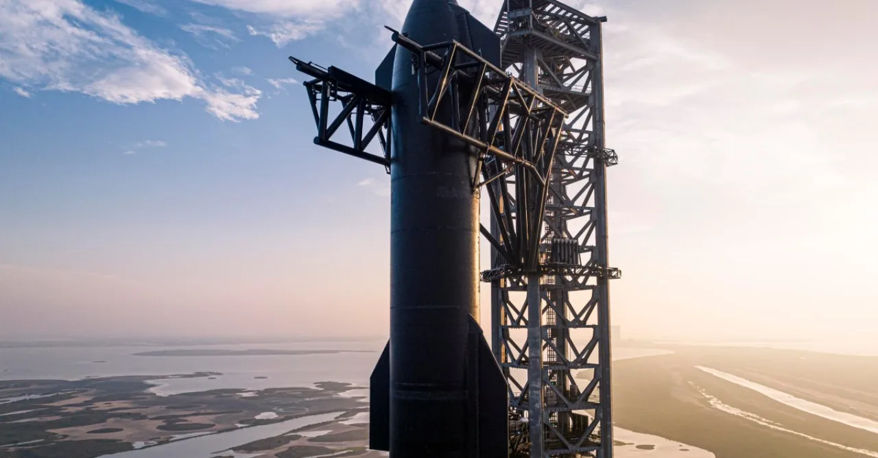 Starship e booster da SpaceX descendo sobre o oceano com paraquedas, enquanto navios de recuperação se aproximam