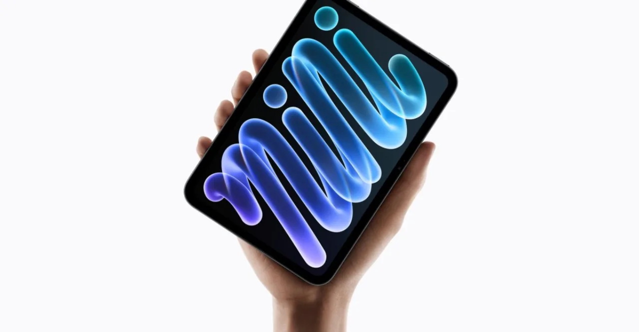 iPad Mini de 8,5" OLED da Apple sobre mesa branca, exibindo tela vibrante e logotipo iluminado