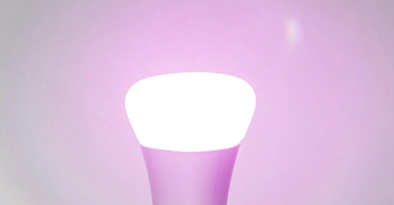 Lâmpada Philips Hue colorida iluminando um tapete de yoga ao lado de halteres e garrafa d'água