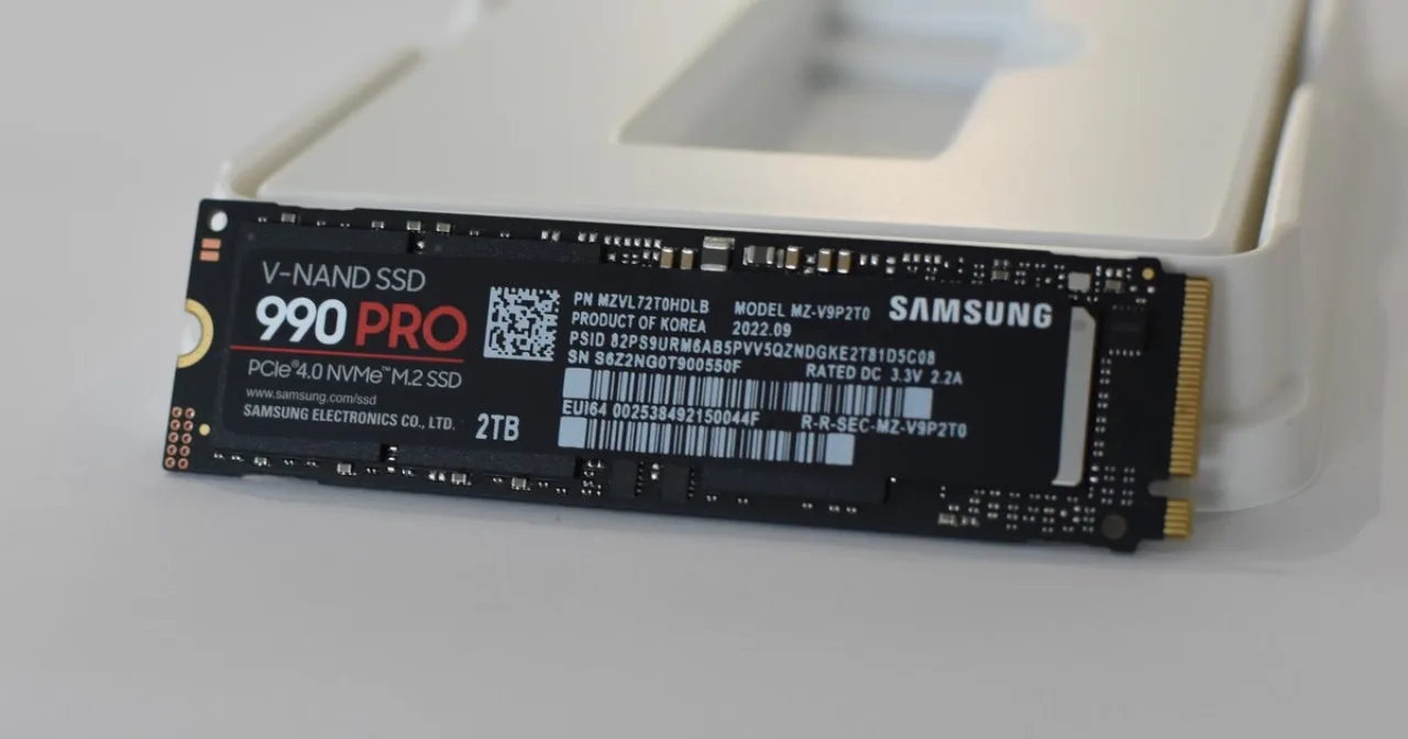 Jogador concentrado, braços musculosos segurando controle, ao lado de placa de RAM e laptop