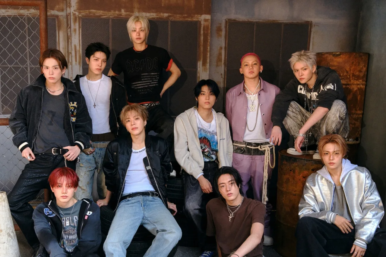 Membros do TREASURE posam em trajes futuristas, ao fundo o título “SHOCK” em neon e o logo da YG Entertainment