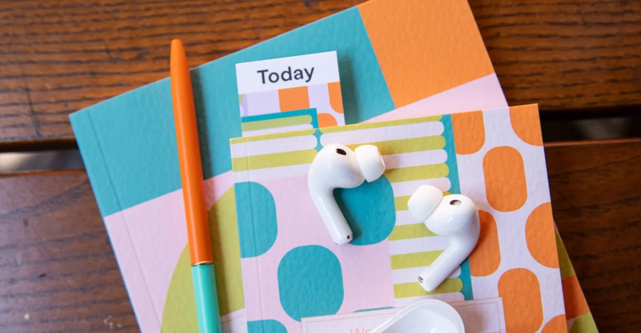 AirPods Pro ao lado de uma lente de câmera, com o logotipo da Apple sobre fundo futurista de circuitos